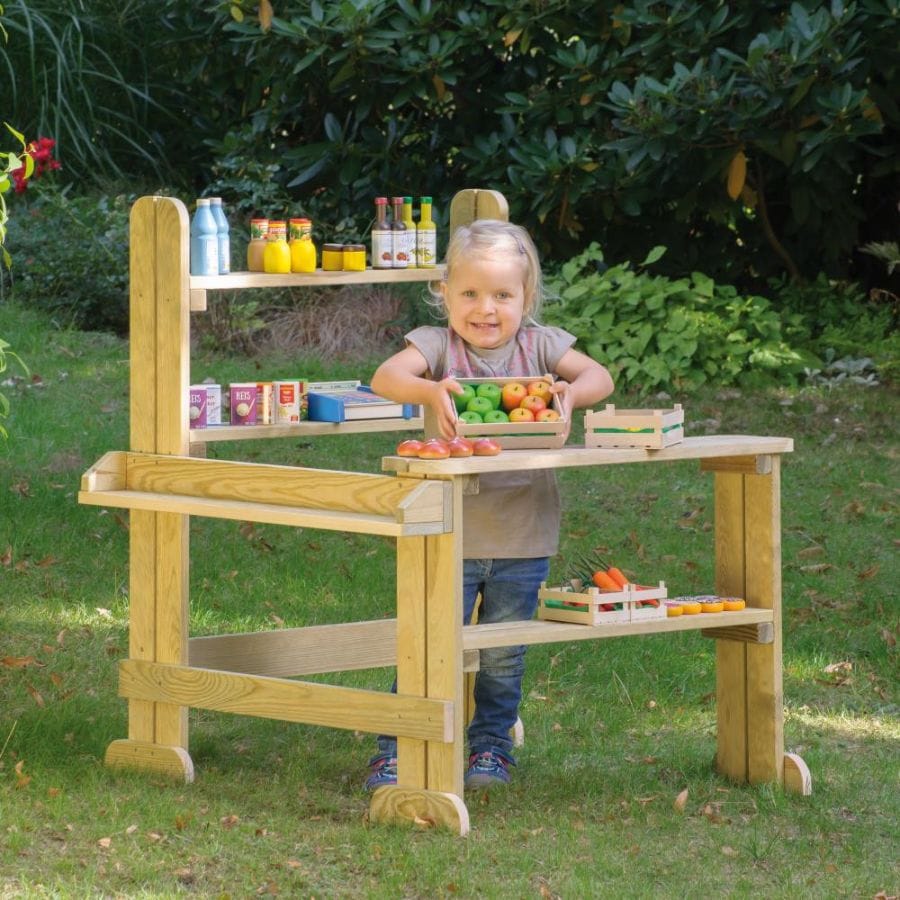 Kleines Mädchen hält Obstkorb am Erzi Outdoor Kaufladen im Garten
